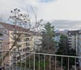 View from a balcony of several apartment buildings, balconies, trees, and a grassy area