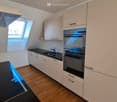 modern kitchen with double oven, granite countertop, dishwasher, white cabinets, window