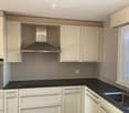Modern kitchen with white cabinets, black countertops, stainless steel range hood, oven, and sink.