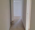 Empty hallway with tiled floor, white walls, and doors on both sides.