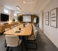 Furnished Room. A conference room with a long table, chairs, a television, a whiteboard, lamps, plants, and a book on the table.