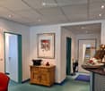 Lobby area with wooden cabinet, small bowl, closed door, framed picture, red chair