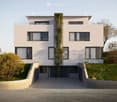 modern 2-story house, white exterior, green climbing plants, balcony, raised ground floor, garage