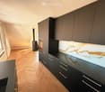 modern kitchen with black cabinets, wooden floor, large windows, marble countertop, built-in oven