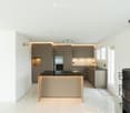 modern kitchen, island with black countertop, built-in oven, central island, modern cabinets, fireplace