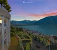 building with a balcony, overlooking a lake and mountains, with surrounding vegetation
