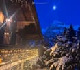 wooden chalet, string lights, snowy mountain in the background