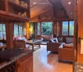 wooden interior, large windows, wooden floor, wooden furniture, fireplace, kitchen area, living area, dining area