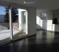 modern design, large windows, sliding glass doors to balcony, white ceiling and walls, black tiled floor