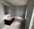 Bathroom with white sink, mirror, bathtub, and shower