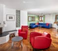 Fireplace, blue sofa, red chairs, wooden floor, dining table, windows