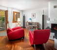 wooden floor, red armchairs, fireplace, wooden bookshelf, table, lamp, picture frame, speakers