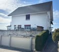 Raised ground floor, 2-story white house, two garages, brick sidewalk