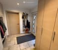 Large entryway with tiled floor, large white doors, white shelves, coat hangings, large wardrobes.
