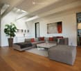 modern living room, gray sofa, white coffee table, gray ottoman, wooden floor, white walls, large painting, lamps, potted plant