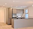 Modern kitchen with light grey cabinets, a central island, and built-in appliances including an oven and sink.