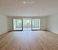 Empty room with light wooden flooring and large sliding glass doors leading to a balcony or outdoor area.