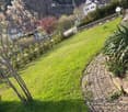 green lawn, brick pathway, trees, bushes, mountain in the background