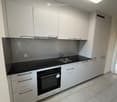 modern kitchen with white cabinets, black countertops, integrated oven and dishwasher, under-cabinet lighting