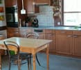 wooden cabinets, wooden table, chairs, oven, stove, sink, countertop, shelves, window