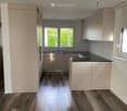 modern kitchen with wooden floor, white cabinets, black countertops, and a window with a view of greenery