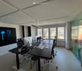 modern office room with desks, chairs, monitors, and a large window with a view of the city