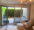sliding glass doors, balcony, white couch, armchair, ottoman, rug, wooden floor, chandelier