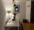 Dining room with a white table, 4 chairs, a lamp, a picture frame, a clock, a rug, and a flower vase