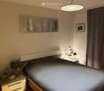A bedroom with a bed, nightstands, a lamp, a picture frame, and a ceiling lamp
