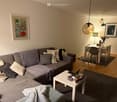 Living room with a gray couch, white coffee table, dining table with chairs, and a rug.