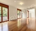 Empty room with wooden flooring, large windows, and white walls. No furniture or equipment present.