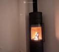 White walls, hardwood floors, black fireplace, wood pile