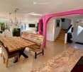 Dining area with wooden table, bench, and chairs, chandelier, pink walls, staircase, and exit sign
