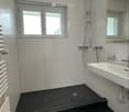 white tiles, black floor, white sink, shower, window, radiator