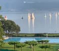 Outdoor swimming pool, green lawn, trees, mountains, lake, sailboats