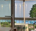 glass door leading to a balcony, pool in the background, lake view, table and chairs
