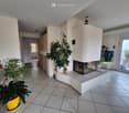 Furnished Room. Modern living room with a central fireplace, large potted plants, and a view through large windows.