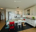 modern kitchen with white cabinets, wooden floor, dining table with chairs, refrigerator, stove, sink, and countertop with plants