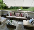 Outdoor patio with wicker furniture, glass coffee table, pillows, and a white awning
