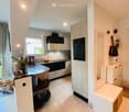 modern kitchen with island, white cabinets, black countertops, white tiled floor, window, mirror, storage, blackboard, mixer, flower vase, bags, books, power outlet