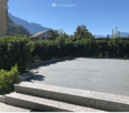Raised ground floor, paved area, bushes, mountains in the background