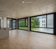 Modern kitchen with a central island, sleek wooden flooring, large windows, and a minimalist design.