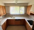 wooden cabinets, white countertops, sink, dishwasher, refrigerator, oven, window with curtains