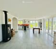 Open plan living room and kitchen, fireplace, dining table, sliding glass doors, kitchen island, white walls, tiled floor