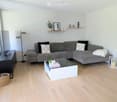 Living room with a gray sectional sofa, white coffee table, black TV stand, floor lamp, and a glass window.