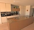 modern kitchen with marble countertop, stainless steel appliances, wooden floor, white cabinets, artwork on the wall