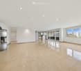Unfurnished Room. Empty room with white walls, beige tiles, and a fireplace. Large windows provide natural light.