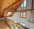 A wooden ceiling with beams, white walls, wooden railings, and windows with wooden frames.