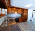 Modern kitchen with wooden cabinets, granite countertop, stainless steel sink, and built-in oven.