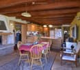 Furnished Room. Dining area with a dining table, chairs, and a fireplace. Wooden cabinets, a refrigerator, and a microwave in the kitchen. A television and a lamp are also present.